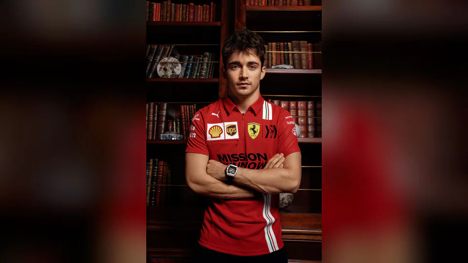 Charles Leclerc i röd racingtröja framför en bokhylla.